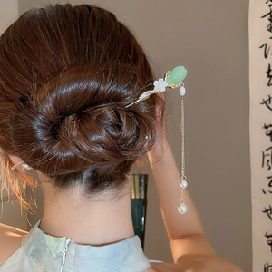 Détail d'une épingle à cheveux rétro avec boutons floraux verts et glands en perles
