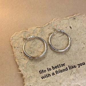 Macro shot of silver twisted geometric hoop earrings on textured vintage fiber paper