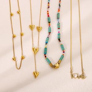 Colliers dorés élégants avec pendentifs cœur, pompon et mot Love sur fond beige