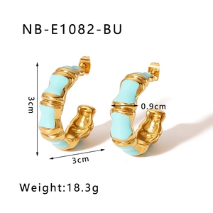 Detail of C-shaped bamboo style earrings in gold metal with light blue enamel finish