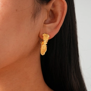 Close-up of 24k gold plated twisted C-shape stud earrings on a model with metallic texture