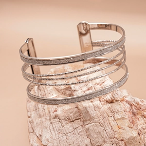 Detailed macro view of multi-layer silver metal bracelet on a natural stone base