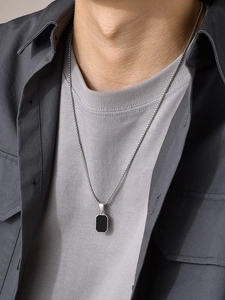 Men's silver Cuban chain necklace with a black rectangular pendant shown on a grey shirt