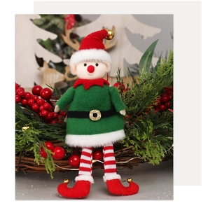 Detail of plush Christmas elf dolls with golden bells and striped socks in a festive wreath