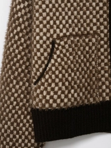 Détail de la veste bomber en maille montrant la poche latérale et l'ourlet côtelé noir