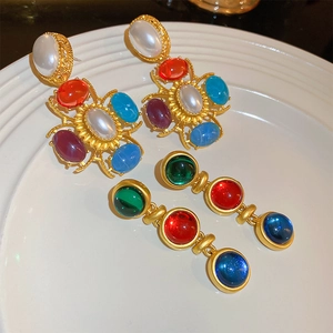 Détail de boucles d'oreilles vintage fleurs avec gemmes colorées et perles sur plat blanc