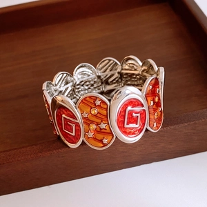 Detail of vintage enamel elastic bracelet with geometric patterns and orange accents