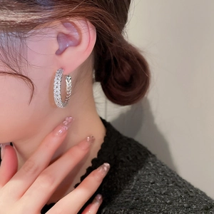 Elegant zircon-encrusted hoop earrings worn by a model in a sophisticated setting