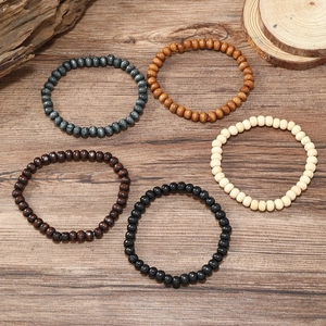 Detailed top view of five handmade multi-layered beaded wood bracelets on a natural surface