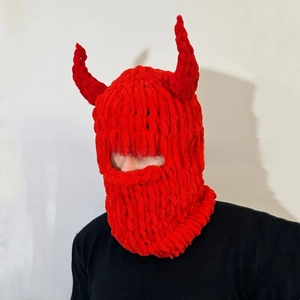 Detail of red knit balaclava with devil horns, featuring thick textured wool yarn