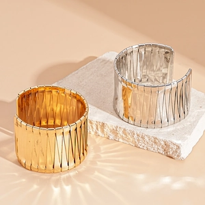Modern gold and silver irregular cuff bracelets with geometric texture on stone pedestals