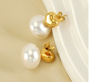 Detailed view of gold-plated heart studs and oval pearls on elegant beige fabric