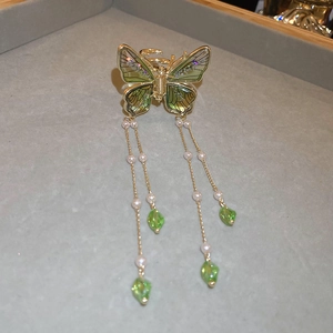 Detail of butterfly hair claw with green wings, white pearls and crystal tassels