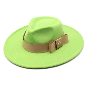 Detail of green wool fedora hat featuring a khaki ribbon and golden bee metallic ornament