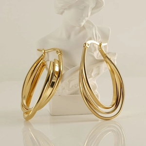 Artistic close-up of gold multilayer hoop earrings displayed on a white marble bust