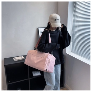 Pink duffel bag with smooth nylon texture shown in use by model near natural window light