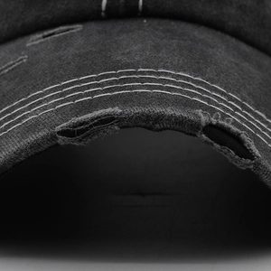 Gros plan d'une casquette en denim délavé avec broderie et détails de bordure effilochés