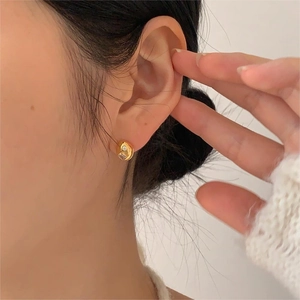 Close-up of a minimalist gold sterling silver stud earring with a small zircon on ear