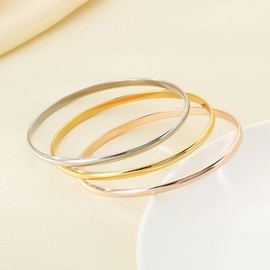 Polished stainless steel bangles in gold, silver, and rose gold stacked on fabric
