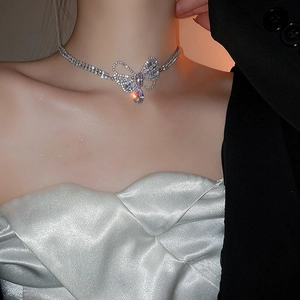 Close-up of a silver zircon hollow bow and teardrop pendant necklace worn by a model
