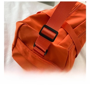 Detail of orange oxford crossbody bag showing adjustable black woven shoulder strap buckle