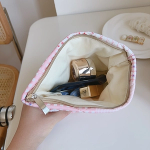 Handheld view of a pink floral quilted makeup bag showing spacious interior storage