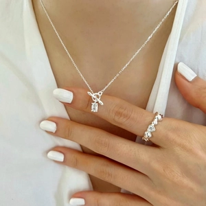 Close-up of geometric zircon necklace with toggle clasp and heart ring on model