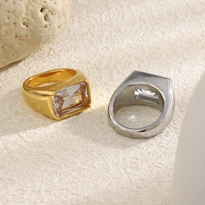 Close-up of gold and silver square-cut zircon rings on a minimalist stone base