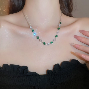 Detail of necklace with alternating green rectangular stones and clear sparkling zircons
