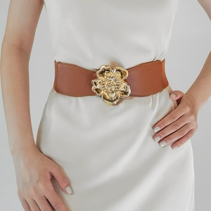 Détail d'une large ceinture élastique avec une grande boucle fleurie dorée en 3D