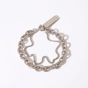 Detail view of layered stainless steel Cuban chain bracelet with smooth metal tag pendant