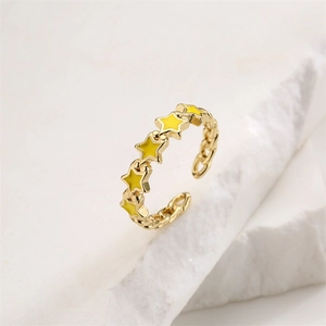 Detail of gold chain band ring featuring yellow enamel stars on white stone background