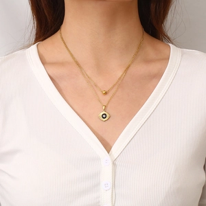 Close-up of a double-layered gold necklace featuring a blue eye pendant on a model