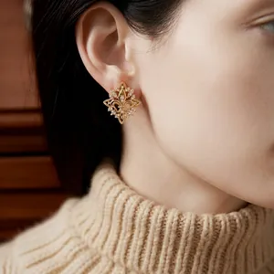 Model wearing vintage 18k gold plated fleur-de-lis stud earrings with cubic zirconia