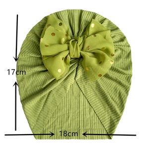 Green knit baby turban hat with gold polka dots and bow detailing for infants