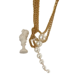 Elegant multi-layer gold pearl necklace with tiered white pearls on a minimalist white base
