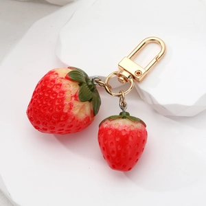 Detailed macro view of dual resin strawberry pendants with golden metal spring hook