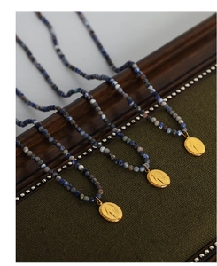 Detail of three beaded necklaces with gold Virgin Mary pendants on a dark wood stand