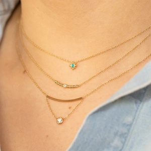 Close-up of layered 925 silver gold-plated necklaces with turquoise and zircon pendants