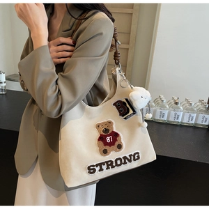 Dettaglio del ricamo a orsetto e tessuto testurizzato su borsa tote beige retrò