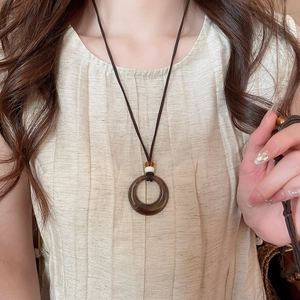 Gros plan du pendentif anneau en acrylique ambré sur cordon avec haut plissé beige