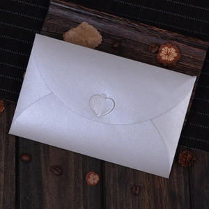 Elegant silver pearlescent envelope with heart-shaped clasp on vintage wood background