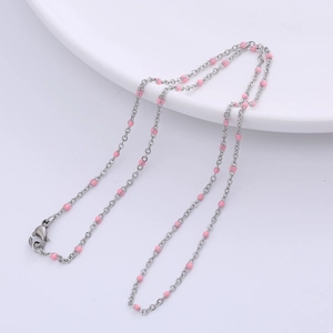 Detail of silver chain necklace with pink beads and lobster clasp on white plate