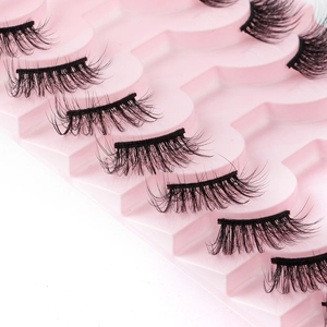 Macro view of dense black synthetic fiber false eyelashes on pink wavy display trays