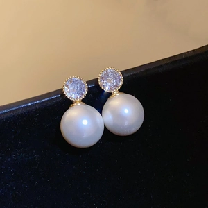 Detailed view of elegant pearl stud earrings with sparkling cubic zirconia and gold plating
