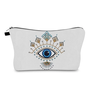 Detailed close-up of white canvas makeup bag featuring golden and blue evil eye embroidery