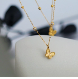 Detailed close-up of golden laser butterfly necklace with engraved texture and small zircon