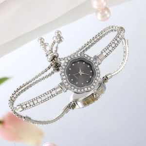 Detail of silver ladies watch with flower dial on reflective surface and pearls