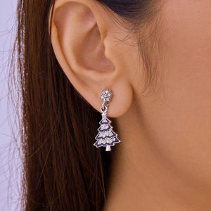 Close-up of a silver Christmas tree earring with sparkling rhinestones worn on ear