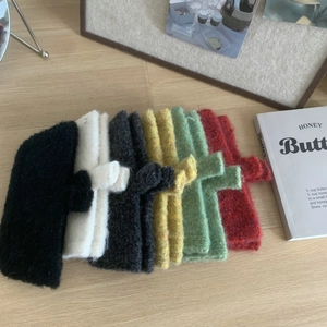 Flat lay of colorful plush knit phone cases in six colors on a cozy wooden desk setup